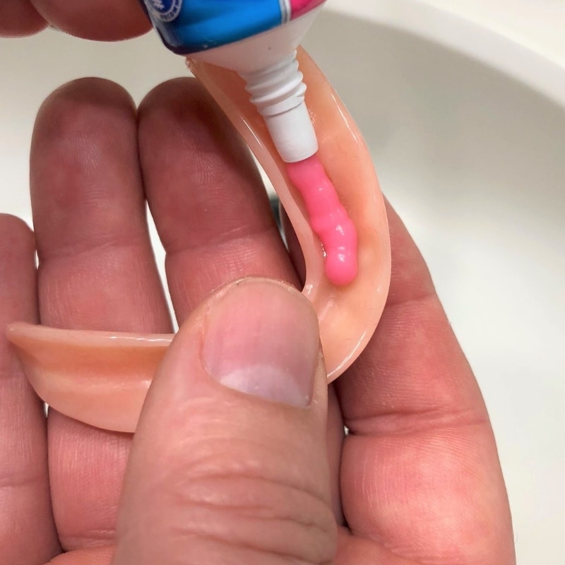Denture glue paste being applied to a denture